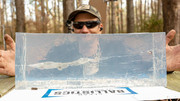 Shooter at the range holding up a clear ballistic gel block with a visible wound channel